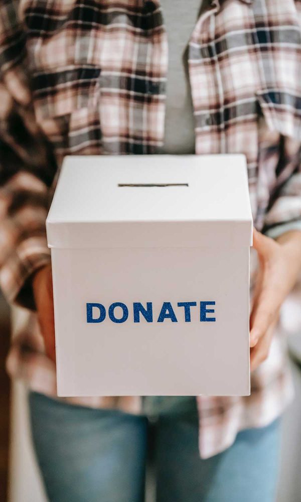 Woman wearing a flannel shirt holding a cardboard donation box
