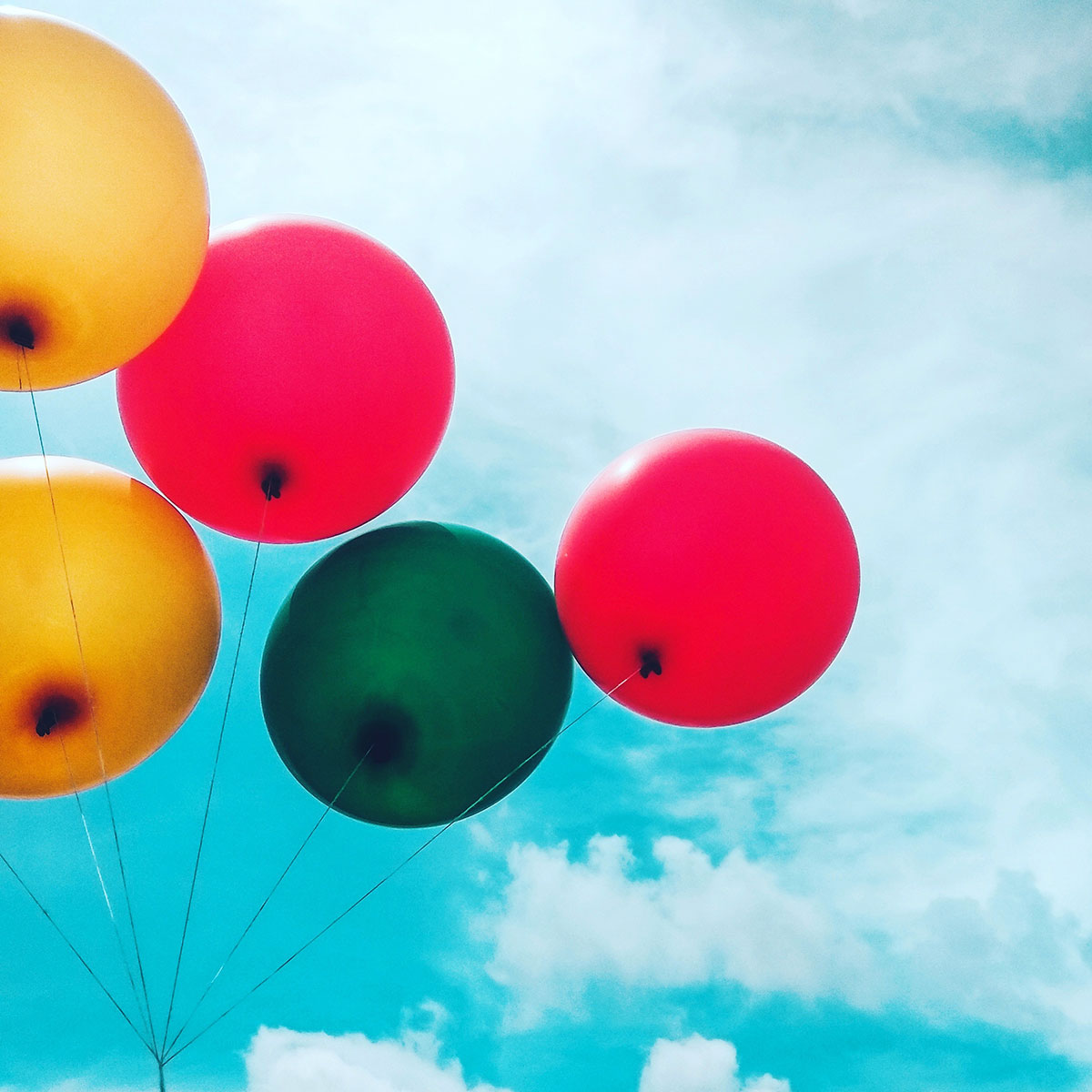 Five colorful balloons on a blue sky background