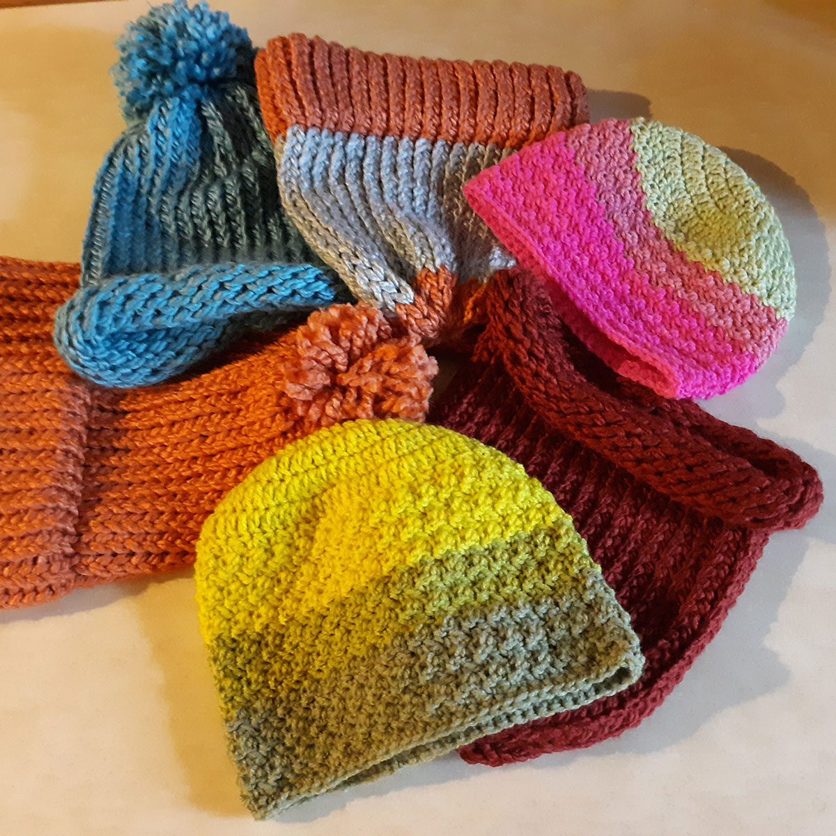 Six colorful knitted hats ready for donation to Hatsgiving