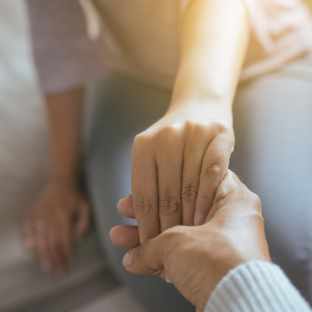 Two people holding hands, being supportive