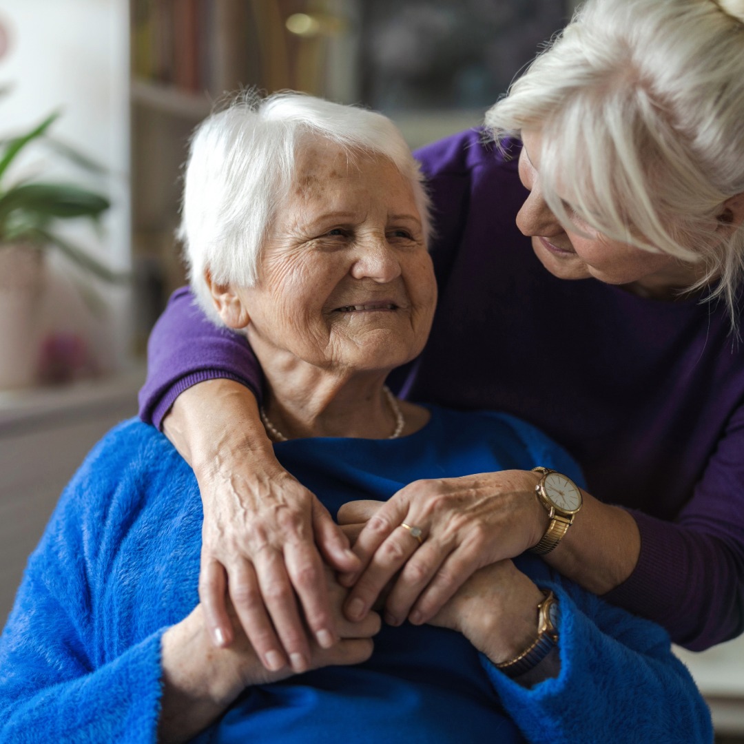 Elderly woman being hugged by a caretaker