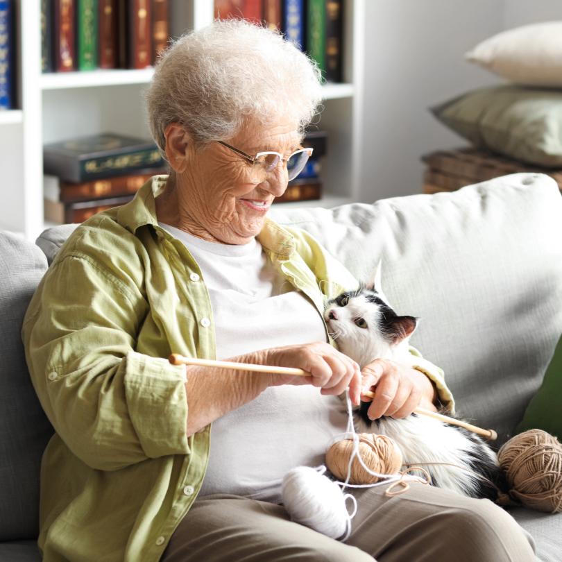 woman happily knitting while cuddling cat